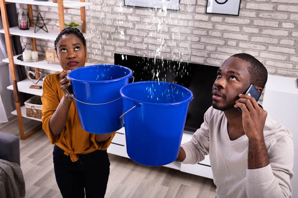 image of a couple collecting water in buckets due to burst water pipe