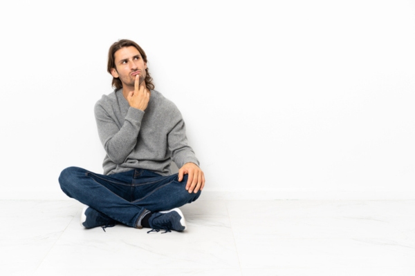 man sitting on the floor while thinking depicting Potential Drawbacks to Consider