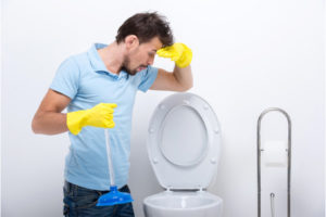 image of a homeowner looking at his clogged toilet