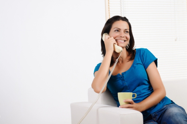 woman using home phone depicting contacting a professional plumber