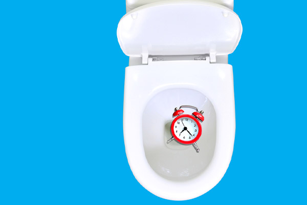 image of an alarm clock in toilet depicting a slow or incomplete toilet flush and airlock
