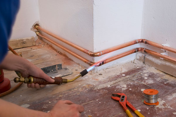 plumber soldering copper pipe and plumbing repair