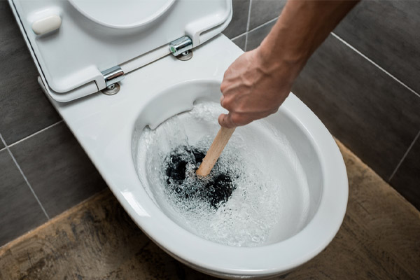 image of a homeowner using plunger for a clogged toilet drain