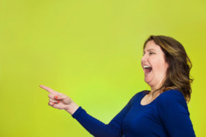 happy laughing woman pointing finger at something depicting funny plumbing facts