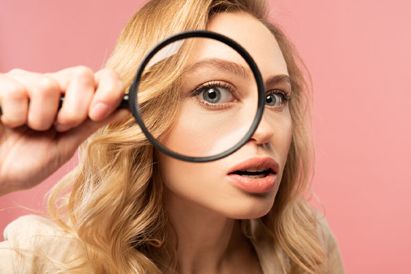 close up of a woman looking through a magnifying glass depicting water leak detection methods