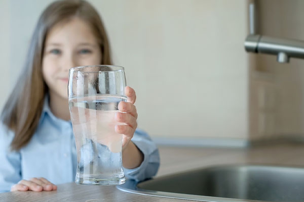 girl holding water depicting water quality impacts plumbing system