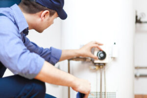 image of plumber adjusting water heater temperature