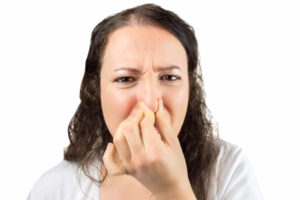 woman plugging nose due to smelly shower drain