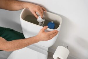 male plumber replacing toilet fill valve