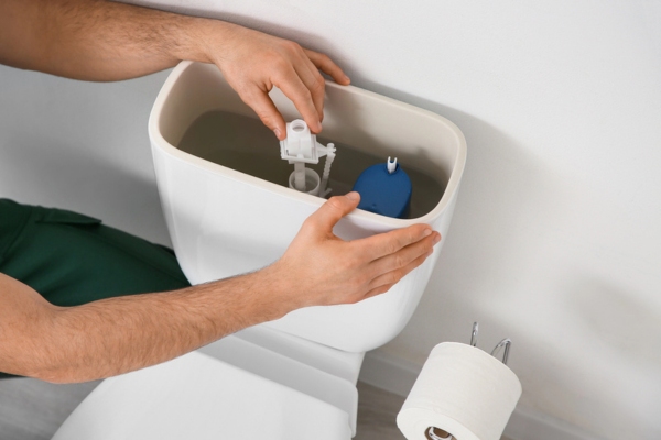 male plumber replacing toilet fill valve