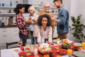 selective focus of a young girl putting bread on the table with guests behind her