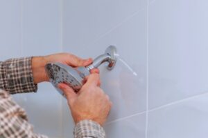 man replacing shower in the bathroom