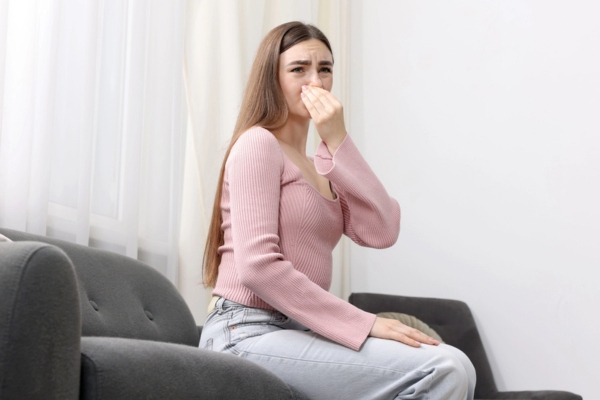woman covering her nose due to musty odor from water leak