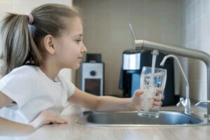 young girl getting drinking water from the tap