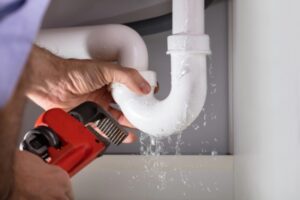 Image Of A Male Plumber Fixing Leaking White Sink Pipe