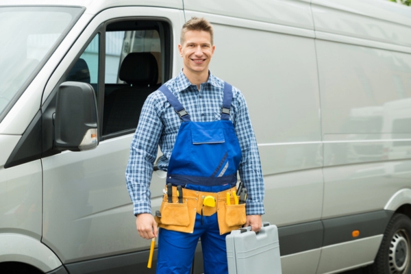 professional plumber carrying tools in front of a service van
